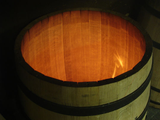 Here you see an oak bourbon barrel being toasted which liquefies sugars in the wood.